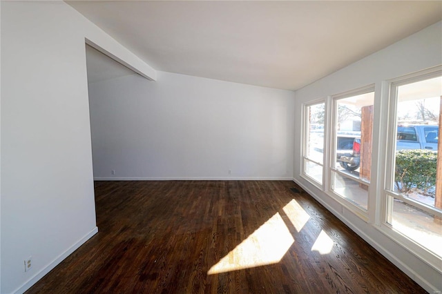 spare room featuring dark wood-type flooring and lofted ceiling with beams