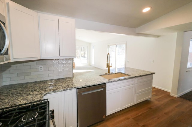 kitchen featuring lofted ceiling, stainless steel dishwasher, sink, white cabinets, and stone countertops