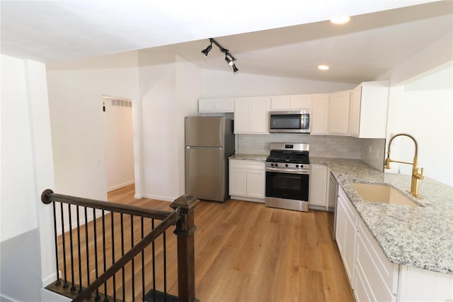 kitchen featuring white cabinetry, stainless steel appliances, decorative backsplash, sink, and light stone counters