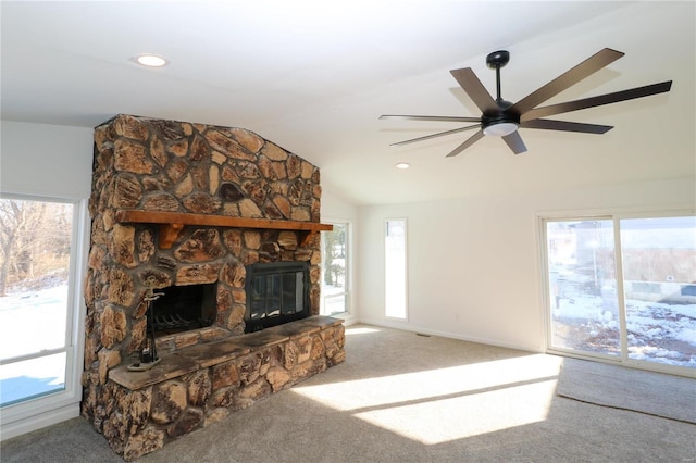 carpeted living room featuring ceiling fan, a stone fireplace, and vaulted ceiling