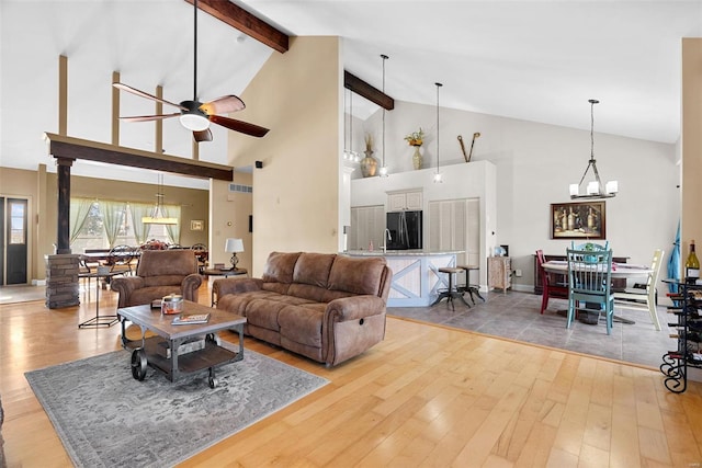 living room with wood-type flooring, ceiling fan with notable chandelier, and vaulted ceiling with beams