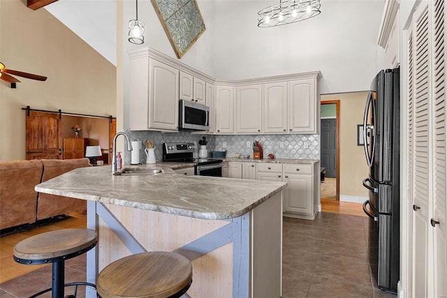 kitchen featuring appliances with stainless steel finishes, a breakfast bar, pendant lighting, sink, and kitchen peninsula