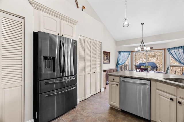 kitchen with decorative light fixtures, lofted ceiling, dark tile patterned floors, a notable chandelier, and stainless steel appliances