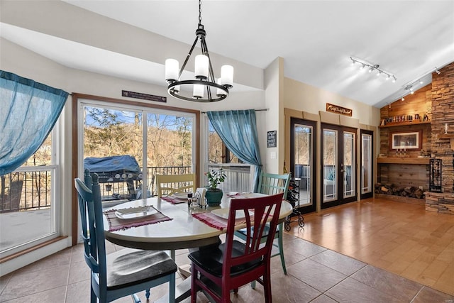 tiled dining room with a chandelier, vaulted ceiling, and a wealth of natural light