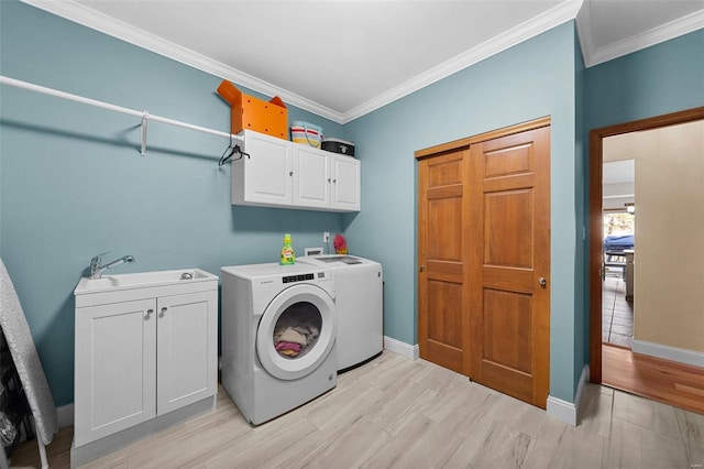 washroom featuring cabinets, ornamental molding, sink, and washing machine and dryer