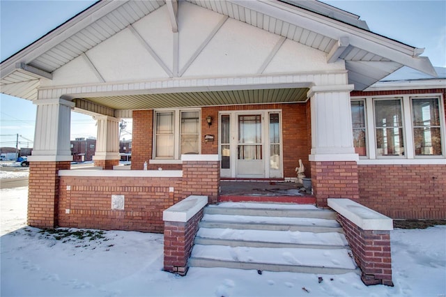 snow covered property entrance featuring covered porch