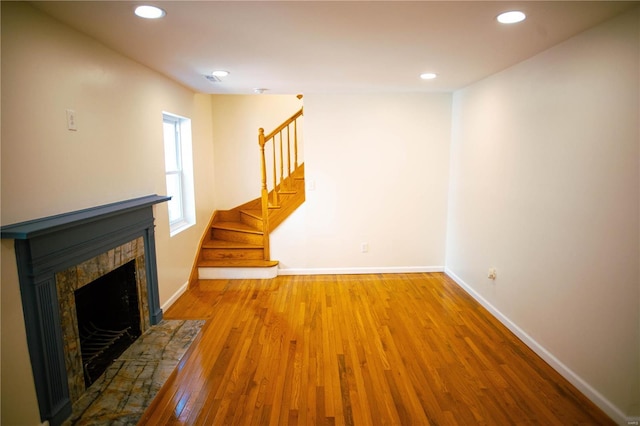 unfurnished living room featuring wood-type flooring and a stone fireplace