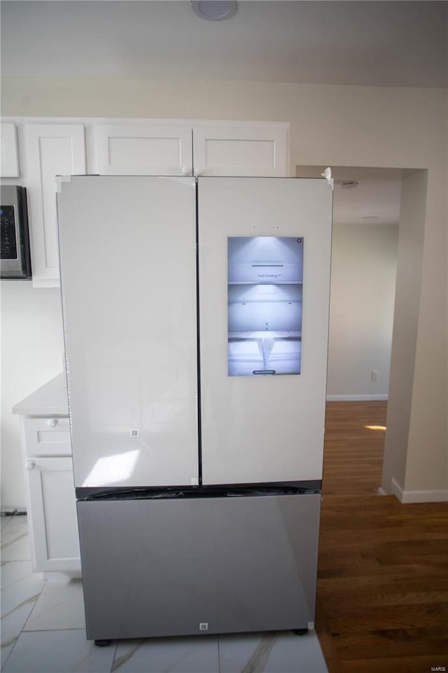 interior space featuring hardwood / wood-style flooring, appliances with stainless steel finishes, and white cabinets