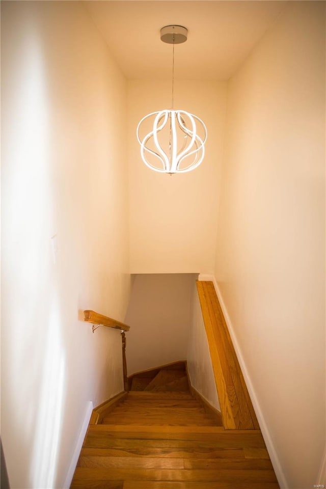 stairs with an inviting chandelier and hardwood / wood-style flooring