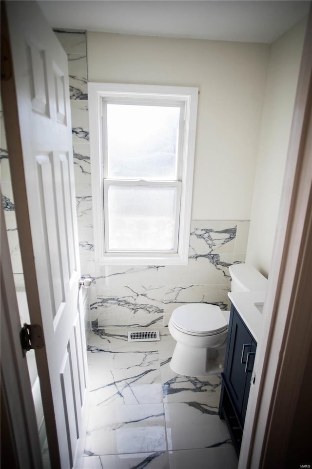 bathroom featuring tile walls, toilet, and vanity