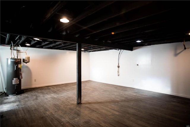 basement featuring dark hardwood / wood-style flooring and electric water heater