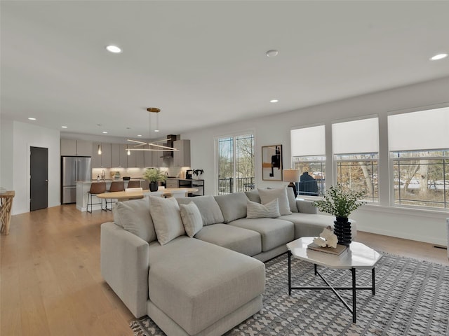 living area with light wood-style floors, baseboards, and recessed lighting