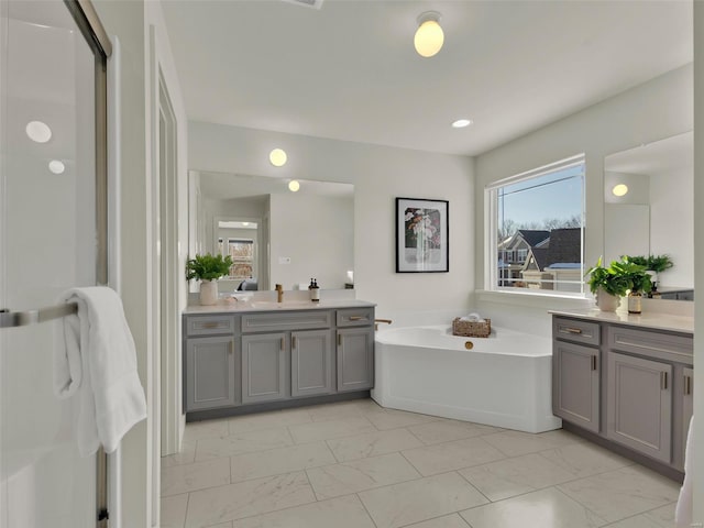 bathroom with a bath, marble finish floor, and vanity