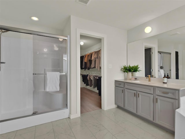 bathroom with marble finish floor, a shower stall, a walk in closet, and vanity