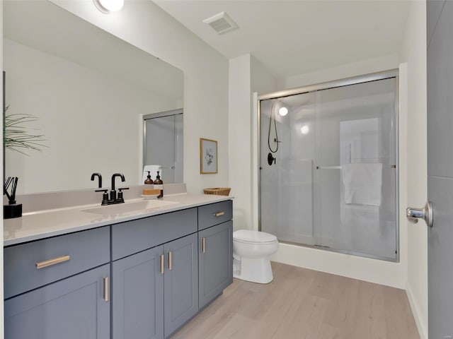 full bath with a stall shower, visible vents, toilet, wood finished floors, and vanity