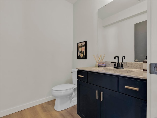 bathroom featuring toilet, baseboards, wood finished floors, and vanity