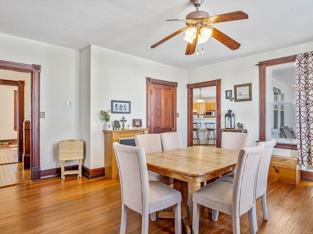 dining area with ceiling fan, a textured ceiling, and light hardwood / wood-style floors