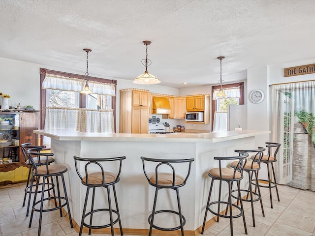 kitchen with light brown cabinetry, white appliances, pendant lighting, and custom exhaust hood