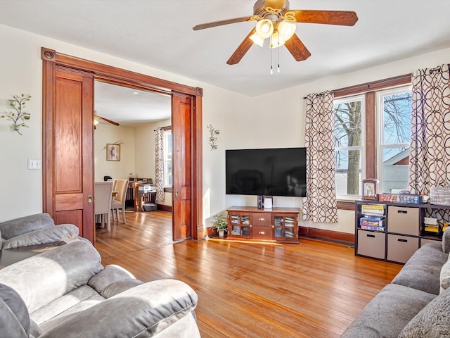 living room with baseboards, ceiling fan, and light wood finished floors