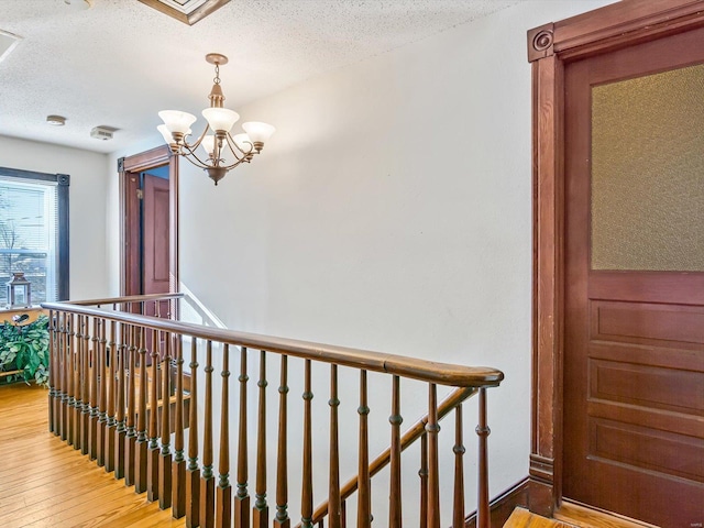 hall featuring hardwood / wood-style flooring, a textured ceiling, and an inviting chandelier