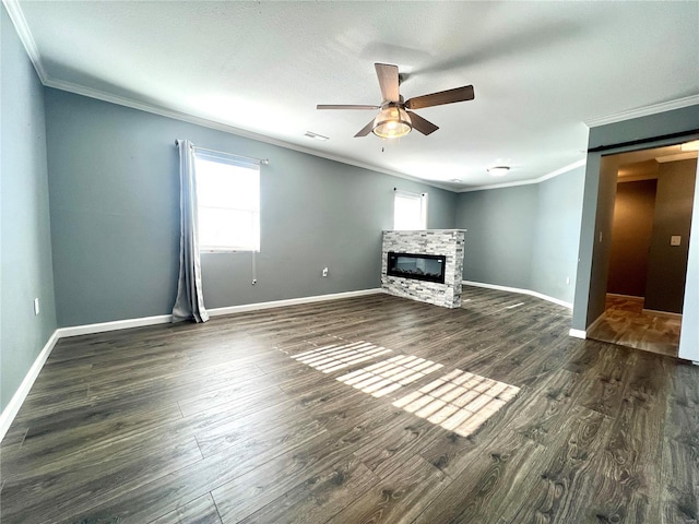 unfurnished living room featuring crown molding, plenty of natural light, and a stone fireplace