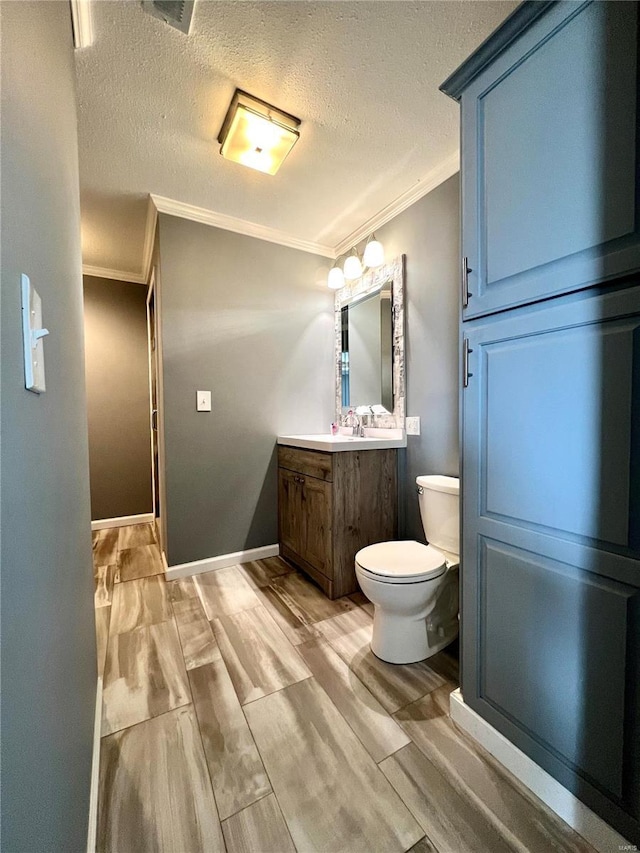 bathroom featuring toilet, ornamental molding, a textured ceiling, and vanity