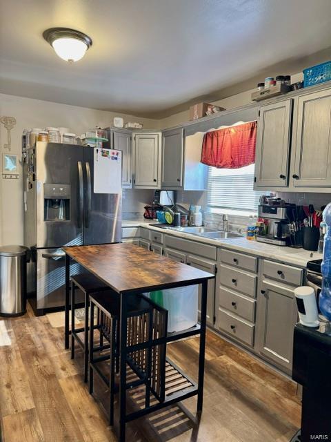 kitchen featuring light wood-type flooring, light countertops, a sink, and stainless steel refrigerator with ice dispenser