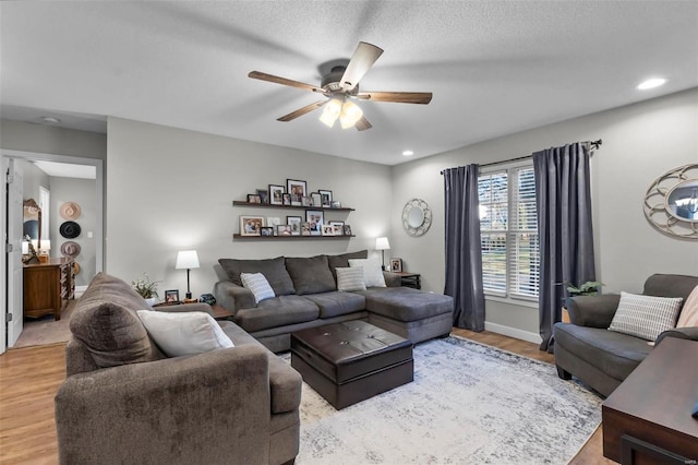 living room with a textured ceiling, ceiling fan, and hardwood / wood-style flooring