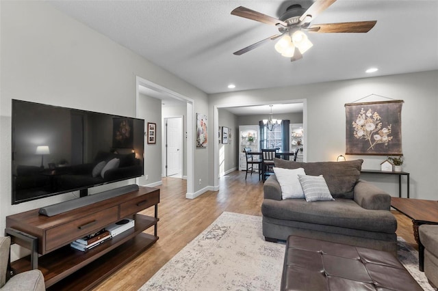 living room with light hardwood / wood-style floors and ceiling fan with notable chandelier