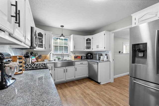 kitchen with decorative light fixtures, tasteful backsplash, sink, stainless steel appliances, and white cabinets