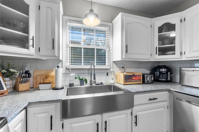 kitchen with backsplash, dishwasher, sink, white cabinetry, and hanging light fixtures