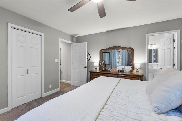 bedroom with connected bathroom, dark colored carpet, sink, a closet, and ceiling fan