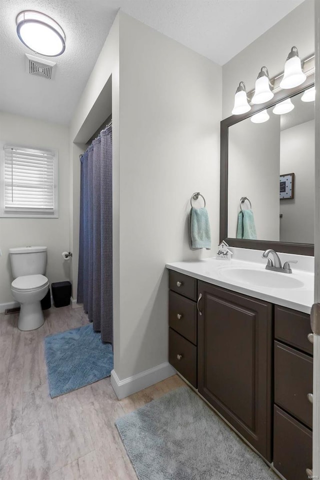 bathroom with hardwood / wood-style flooring, a textured ceiling, toilet, and vanity