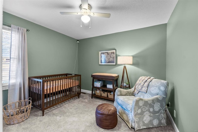 bedroom with ceiling fan, carpet flooring, and a crib