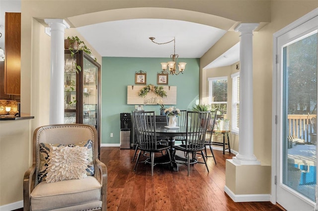 dining area with an inviting chandelier, dark hardwood / wood-style flooring, and decorative columns