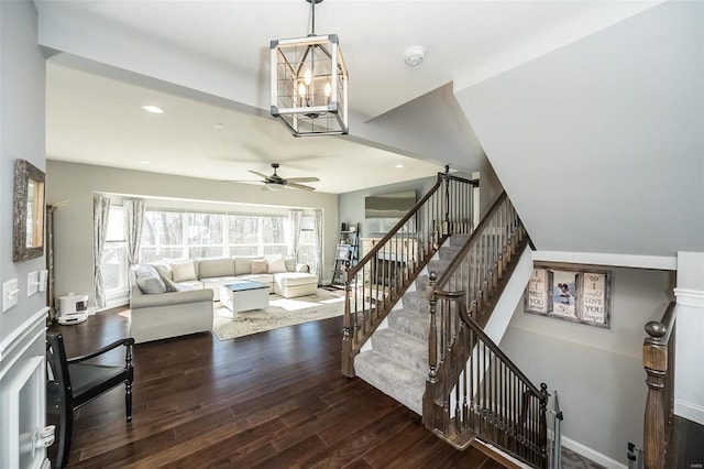 living room featuring dark wood-type flooring and ceiling fan with notable chandelier