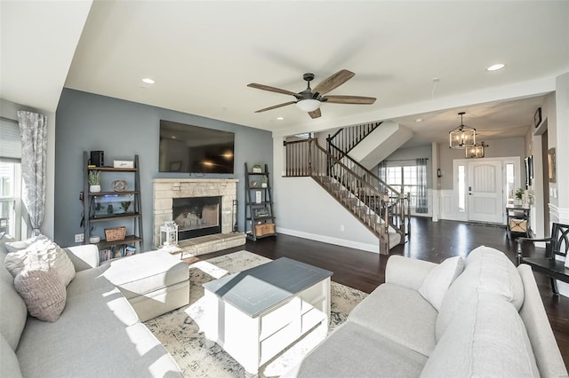 living room with ceiling fan with notable chandelier, a fireplace, and dark hardwood / wood-style floors