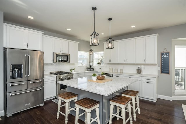 kitchen with white cabinetry, hanging light fixtures, dark hardwood / wood-style floors, a center island, and high quality appliances