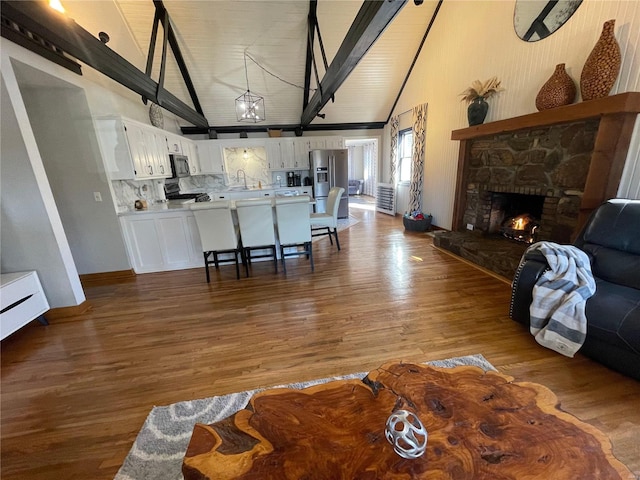 living room with high vaulted ceiling, a fireplace, hardwood / wood-style flooring, and beamed ceiling