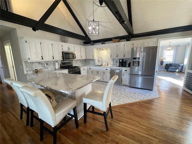 kitchen featuring appliances with stainless steel finishes, tasteful backsplash, hanging light fixtures, white cabinets, and beamed ceiling