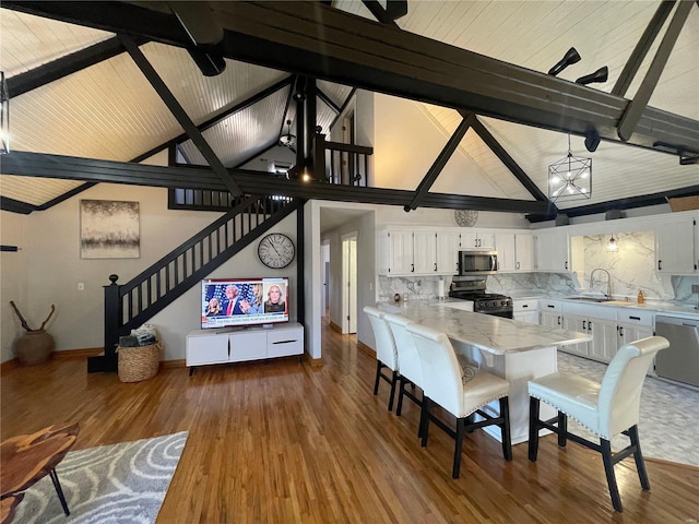 kitchen with white cabinets, appliances with stainless steel finishes, decorative backsplash, sink, and high vaulted ceiling