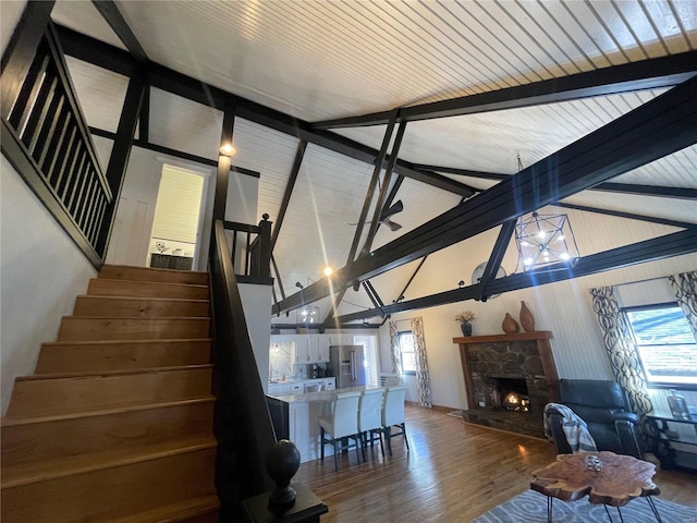 interior space with hardwood / wood-style flooring, a stone fireplace, beamed ceiling, and a healthy amount of sunlight