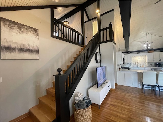 stairway with high vaulted ceiling, hardwood / wood-style floors, beam ceiling, and wood ceiling