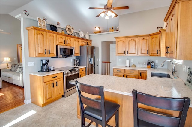 kitchen with a kitchen bar, kitchen peninsula, ceiling fan, appliances with stainless steel finishes, and sink