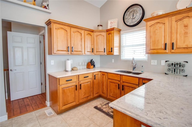 kitchen featuring light tile patterned floors, light stone countertops, and sink