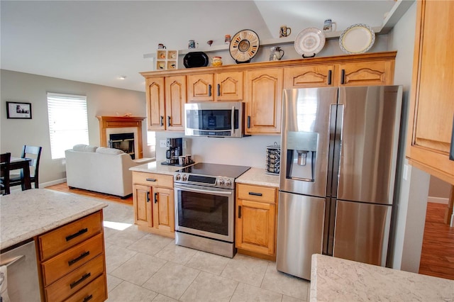 kitchen with light tile patterned floors, vaulted ceiling, and appliances with stainless steel finishes