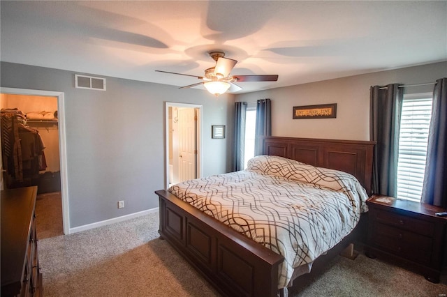 carpeted bedroom with ceiling fan, a walk in closet, and a closet