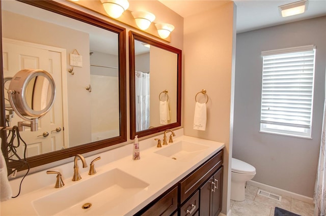 bathroom with tile patterned floors, toilet, vanity, and a healthy amount of sunlight