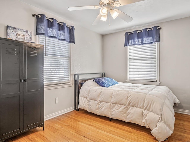 bedroom featuring ceiling fan, multiple windows, and wood-type flooring