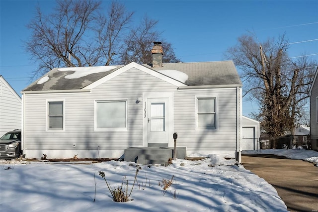 snow covered rear of property featuring a garage